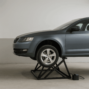 A modern gray sedan raised on a portable black scissor car lift inside a compact garage. The space is minimal and clean, with smooth concrete flooring and neutral walls, highlighting the lift’s space-saving and efficient design.